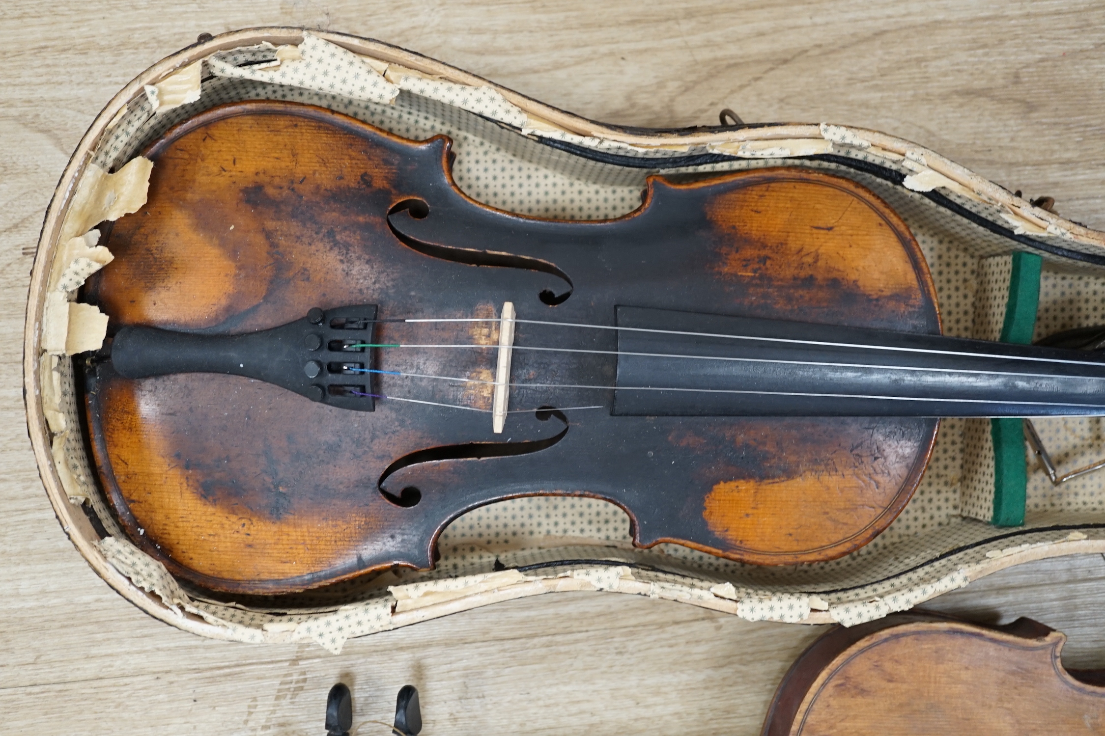 Two early 20th century violins, one in the remains of a case, both for restoration, length of bodies, 35.5cm and 36cm